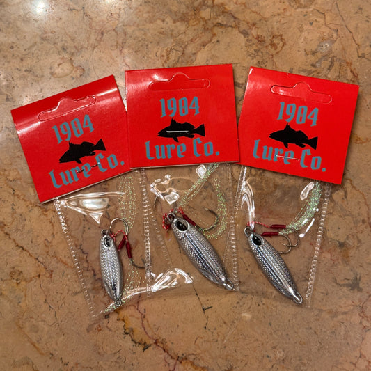 Fishing lures with red boxes labeled '1984 Lure Co.' on a marble surface.